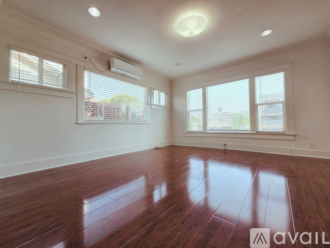 A room with wooden floors and a large window with blinds.