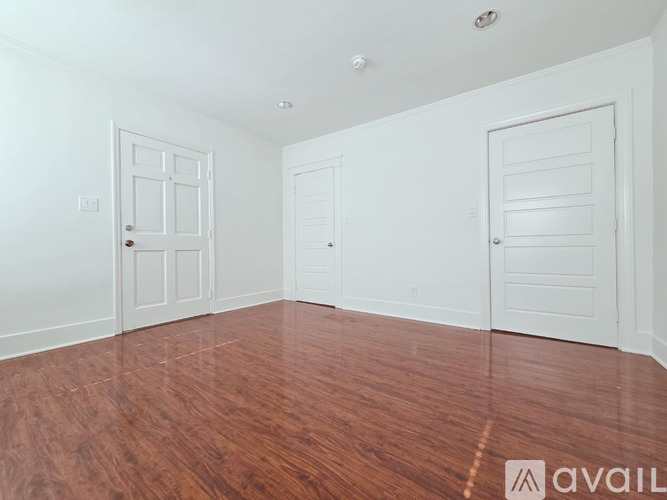 A room with white walls and wooden flooring with two doors.