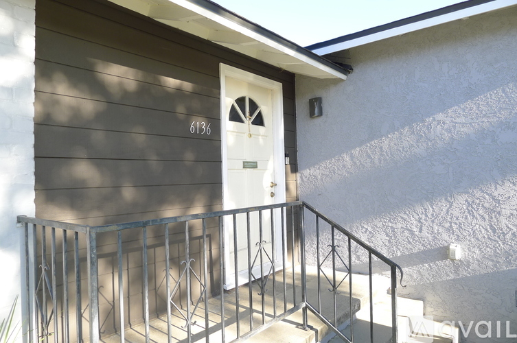 A house numbered 6136 with a white door and a metal staircase.