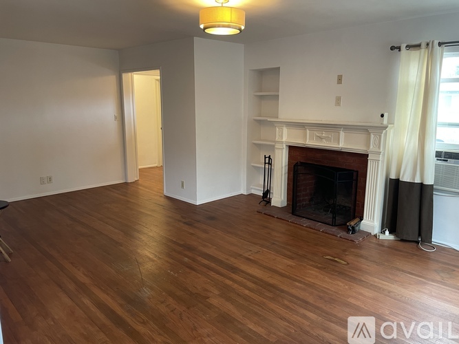 A living room with a fireplace and wooden floors.
