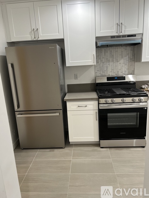 A kitchen with a stainless steel refrigerator, a white oven, and white cabinets.