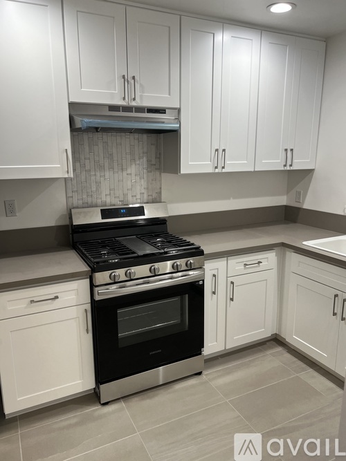A kitchen with a black stove top oven and white cabinets.