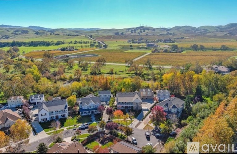 A suburban neighborhood with houses and trees in the foreground and a mountain range in the background.