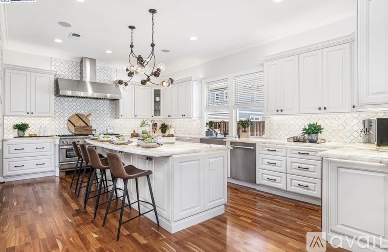 A kitchen with white cabinets and a wooden floor.