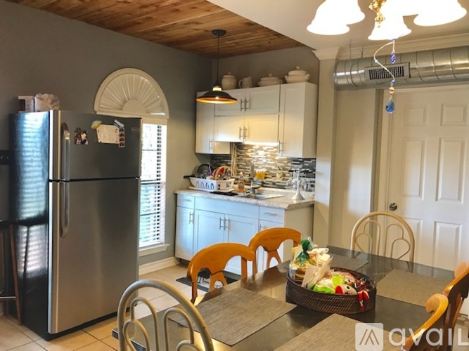 A kitchen with a refrigerator, chairs, and a table.