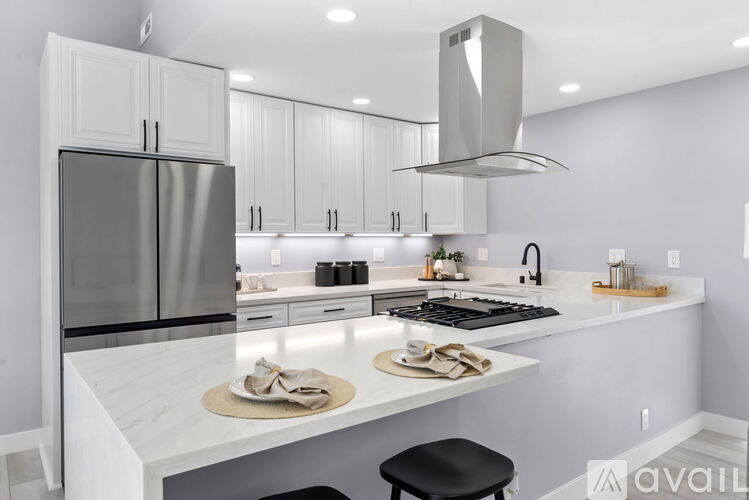 A modern kitchen with white cabinets and a marble countertop.