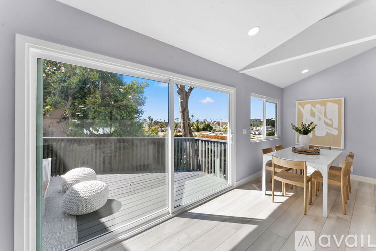 A modern dining room with a view of the backyard through the sliding glass doors.