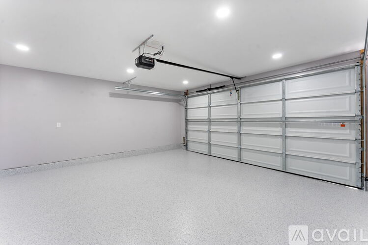 A spacious garage with a closed white door and a security camera mounted on the ceiling.