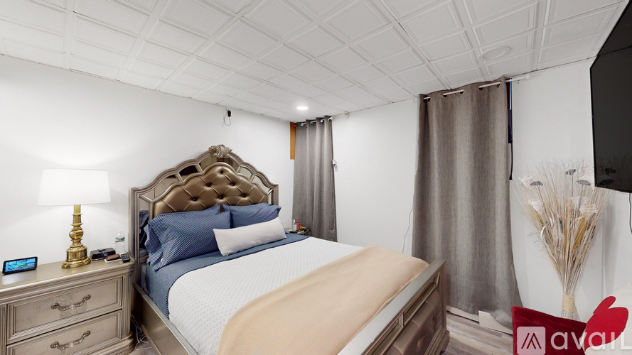 A bedroom with a large bed, a lamp, and a vase of flowers.