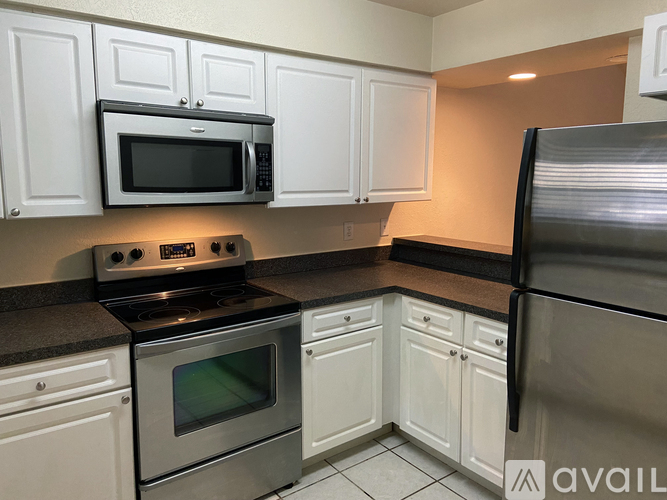 A kitchen with white cabinets and a black countertop.