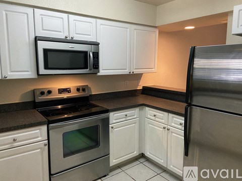 A kitchen with white cabinets and a black countertop.