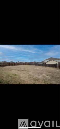A grassy field with a fence and a house in the distance.