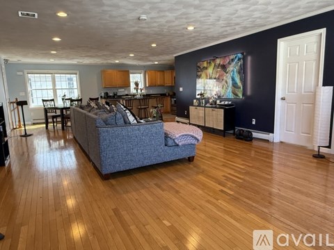A living room with a blue couch and wooden floors.