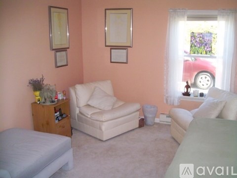 A living room with a white couch, a wooden cabinet, and two framed pictures on the wall.