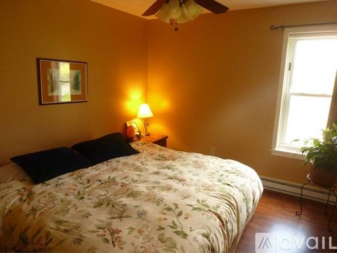 A bedroom with a floral bedspread and a ceiling fan.