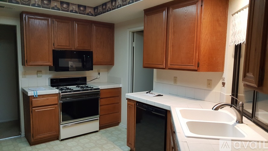 A kitchen with wooden cabinets and a black microwave above the stove.