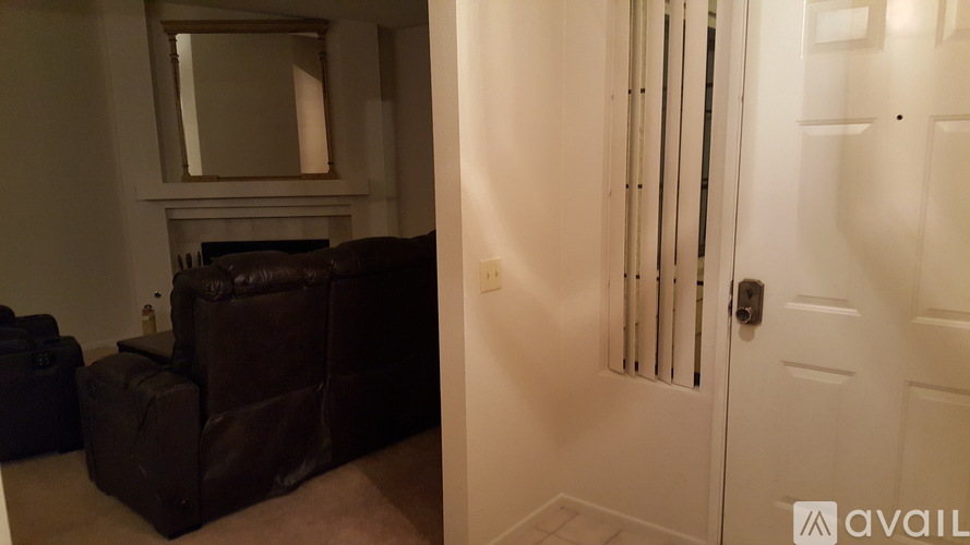 A room with a white door and a mirror above the fireplace.