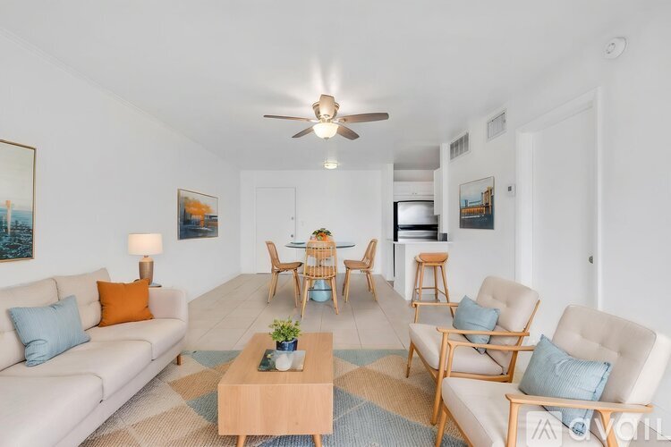 A living room with a white couch, two chairs, a coffee table, and a ceiling fan.