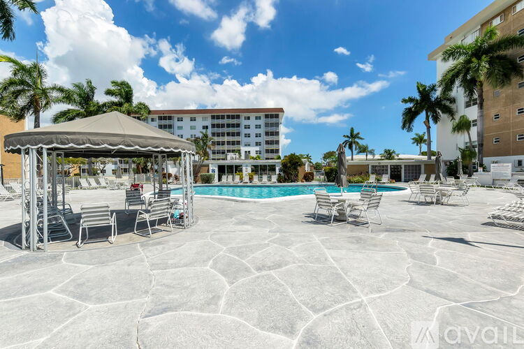 A pool area with a gazebo and chairs.