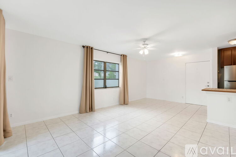 A spacious room with a window and a fan on the ceiling.