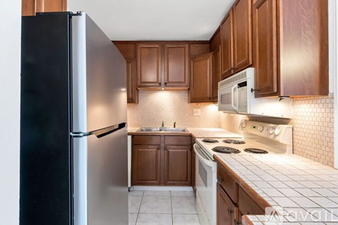 A kitchen with brown cabinets and a black refrigerator.