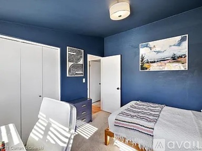 A bedroom with blue walls and a bed with a striped blanket.