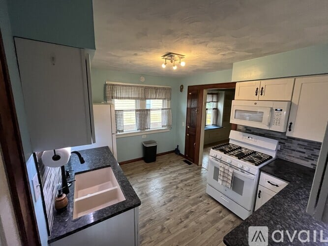 A kitchen with a sink, stove, and microwave.