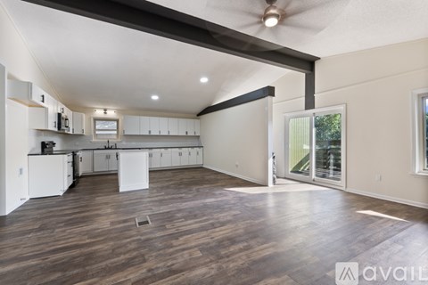 A spacious kitchen with white cabinets and a ceiling fan.