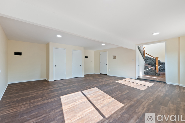 A spacious room with wooden flooring and white walls.
