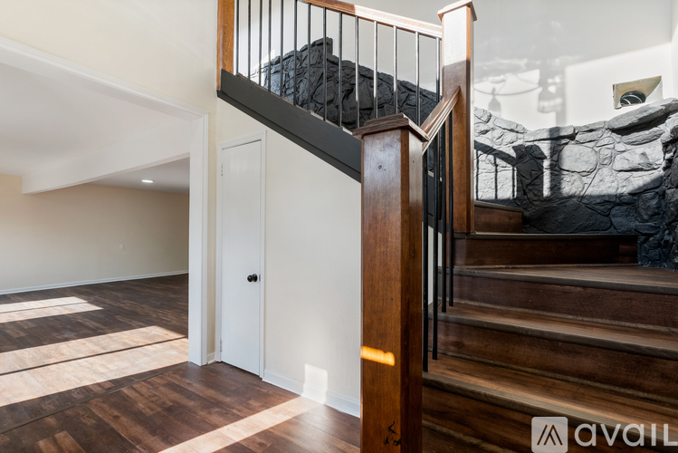 A wooden staircase with a glass railing leads to a bedroom.