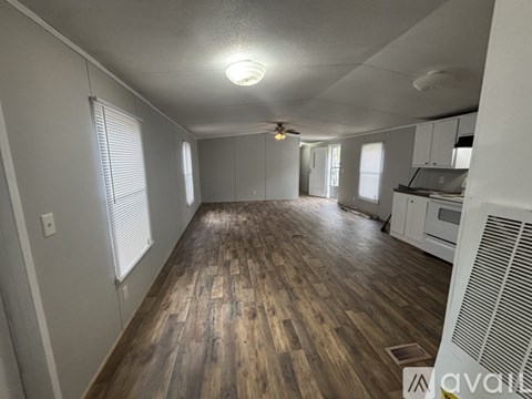 A spacious room with wooden flooring and a ceiling fan.