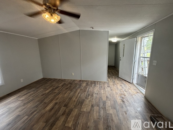 A room with a ceiling fan and wooden flooring.