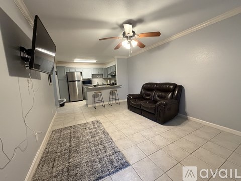 A living room with a black leather couch and a ceiling fan.