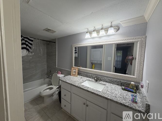 A bathroom with a granite countertop and a large mirror.
