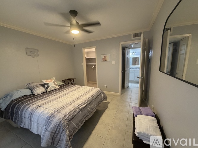 A bedroom with a bed, a ceiling fan, and a mirror.