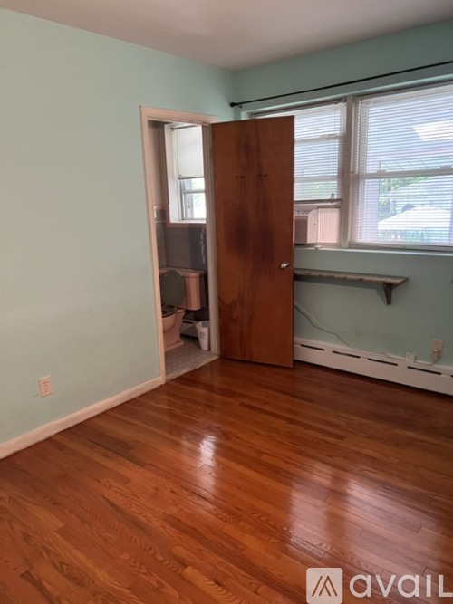 A room with a wooden floor and a door leading to a hallway.
