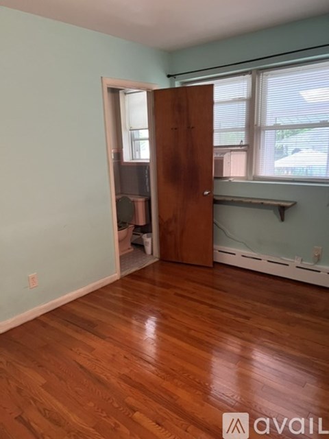 A room with a wooden floor and a door leading to a hallway.