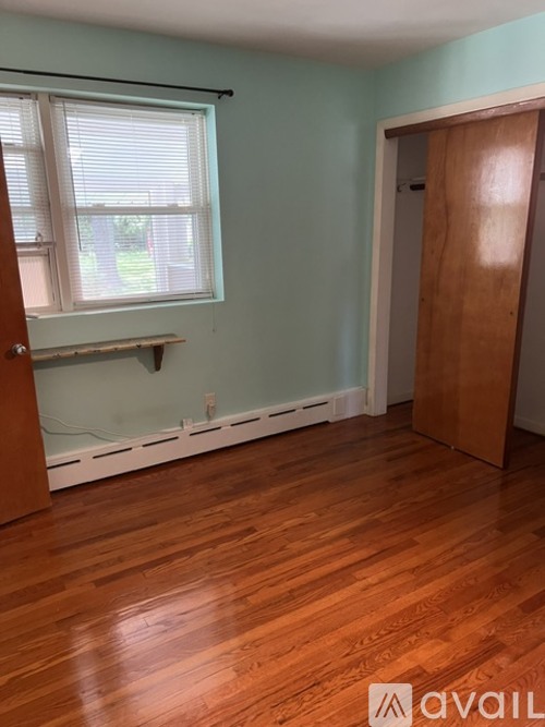 A room with wooden floors and a window with blinds.