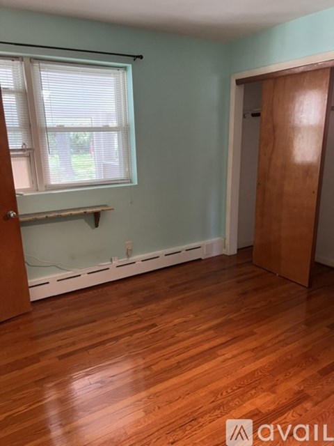 A room with wooden floors and a window with blinds.