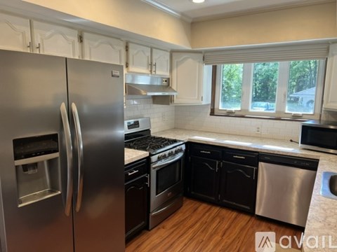 A kitchen with a stainless steel refrigerator and black appliances.