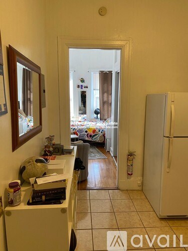 A kitchen with a white fridge and a doorway leading to a living room.