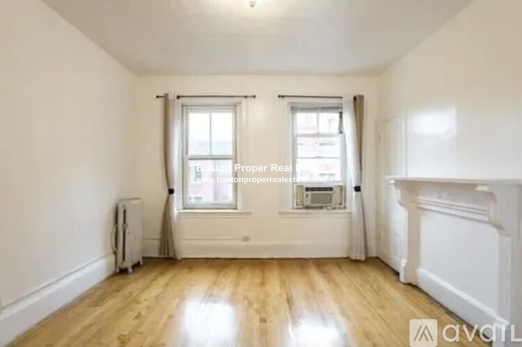 A well-lit room with wooden floors and a fireplace.