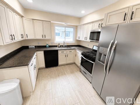 A kitchen with white cabinets and a black countertop.