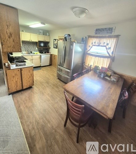 A kitchen with a refrigerator, table and chairs.