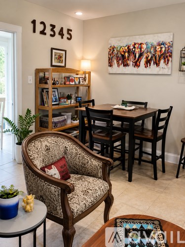 A living room with a chair, a table, and a painting on the wall.