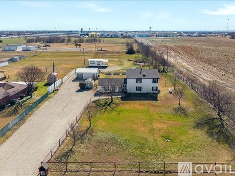A large open field with a few buildings and a fence.