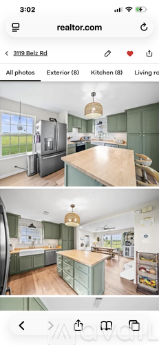 A kitchen with green cabinets and a wooden island.