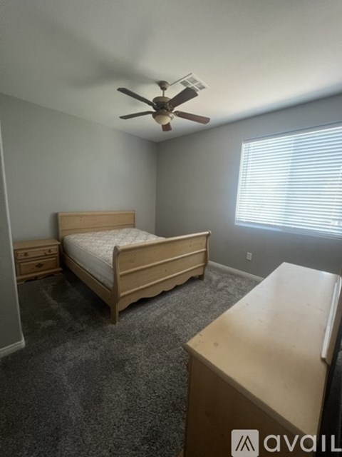 A bedroom with a bed, dresser, and a ceiling fan.