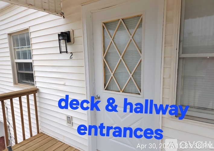 A white house with a deck and a door entrance.