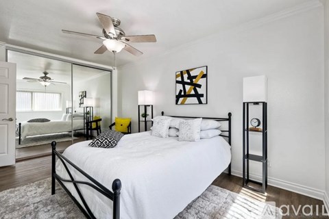 A bedroom with a white bed and a ceiling fan.